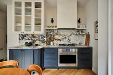 a dark apartment kitchn with marble counters and tambour corner units