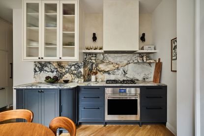 a dark apartment kitchn with marble counters and tambour corner units