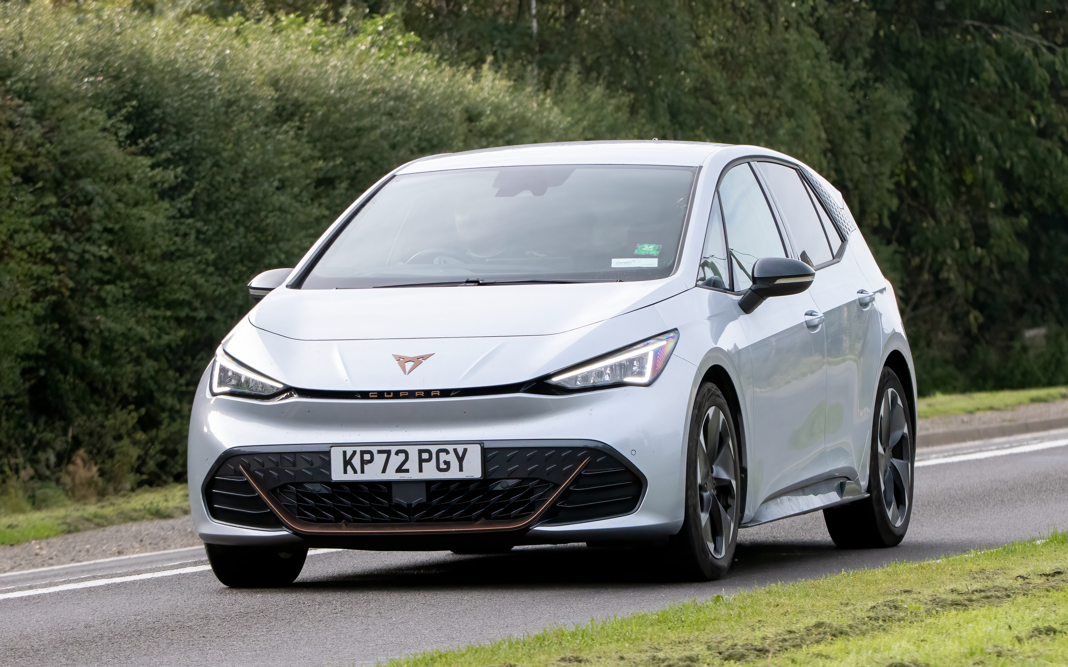 Cupra Born V2 EV electric car driving on an English country road.