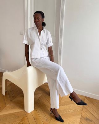 a woman wears a white button-down shirt with matching pants