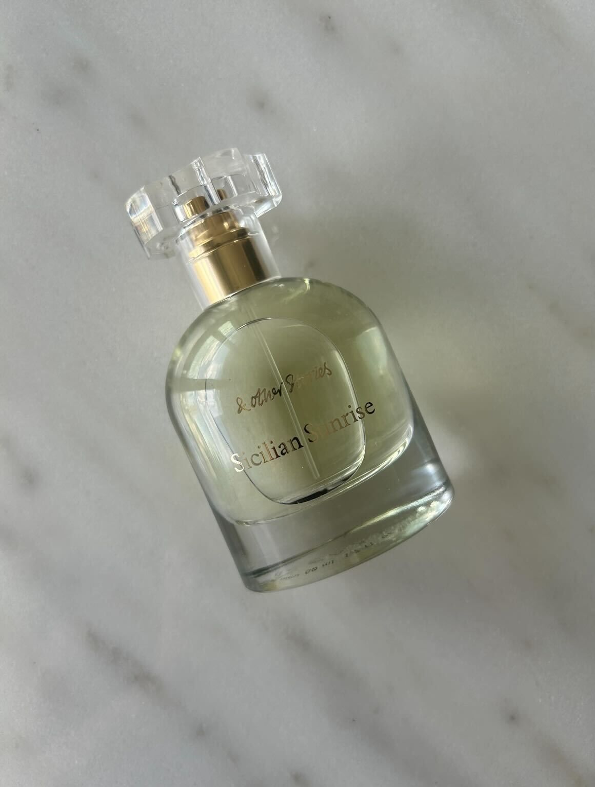 A photo of &amp; Other Stories Sicilian Sunrise perfume bottle on a marbled surface