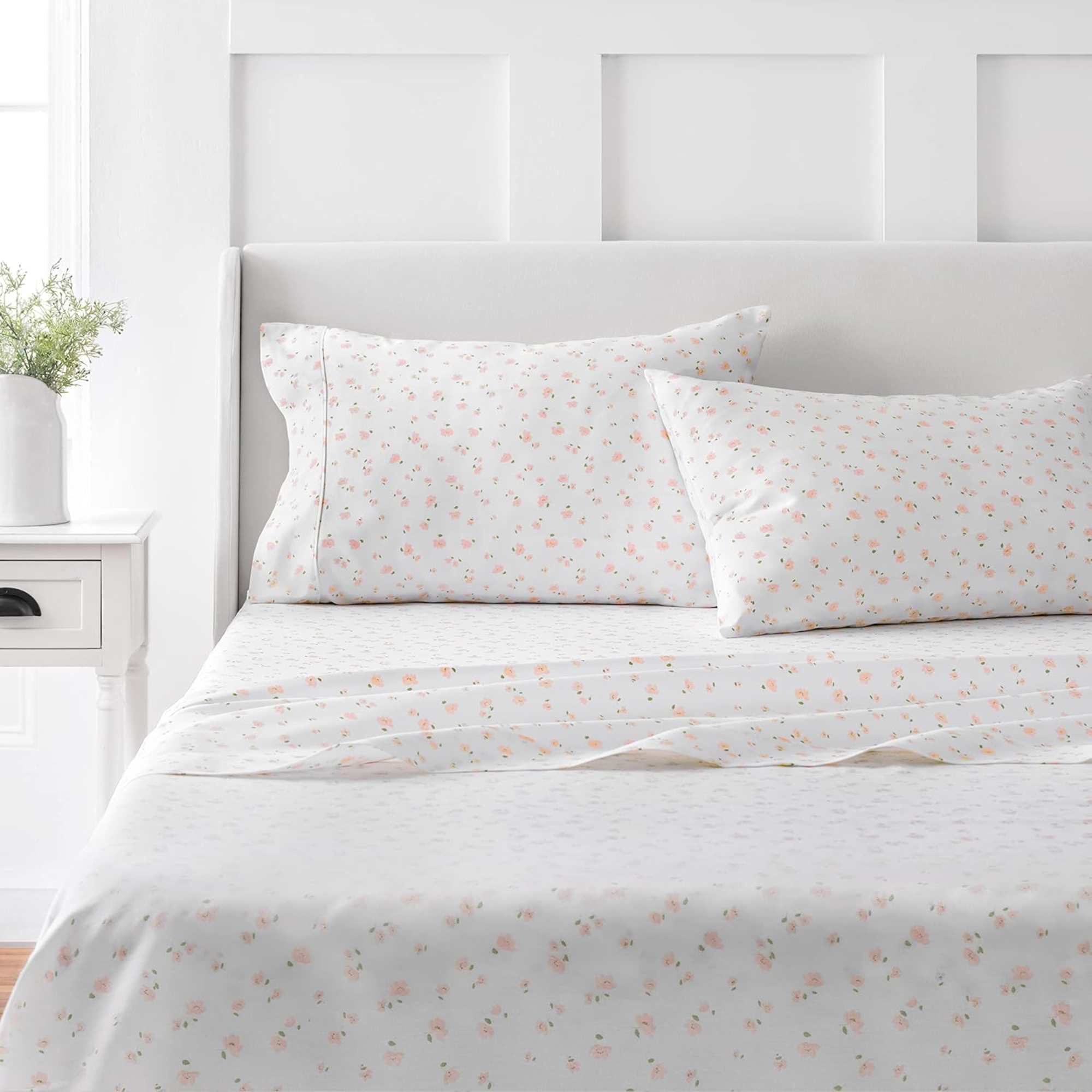 a bed with a set of white floral sheets and two pillows