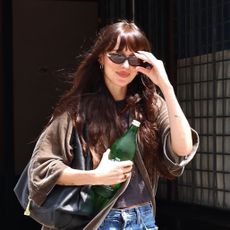 Dakota Johnson wearing a velvet jacket, T-shirt, jeans, and Gucci bag