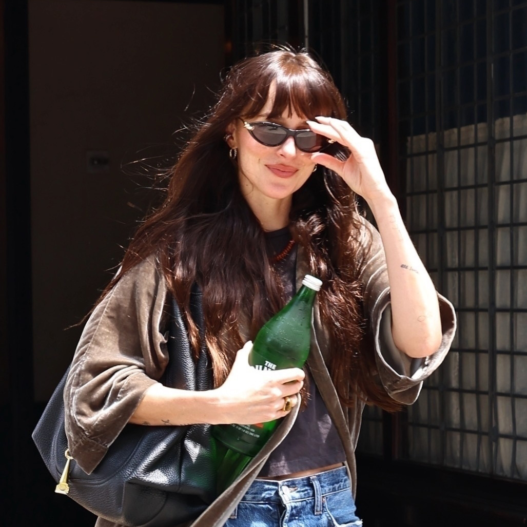 Dakota Johnson wearing a velvet jacket, T-shirt, jeans, and Gucci bag
