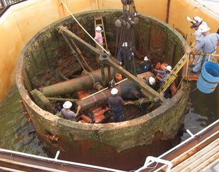 Restorers examine the USS Monitor gun turret.