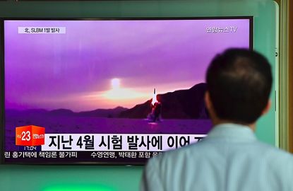 A man watches file footage of a North Korean missile launch.