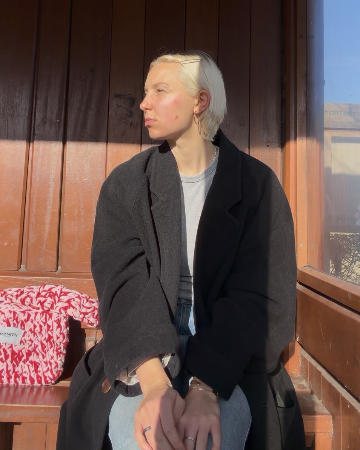 A woman sits waiting at a bus stop