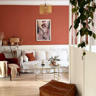 Living room with terracotta half wall and white paneled half wall, with squishy neutral couch, and modern artwork.