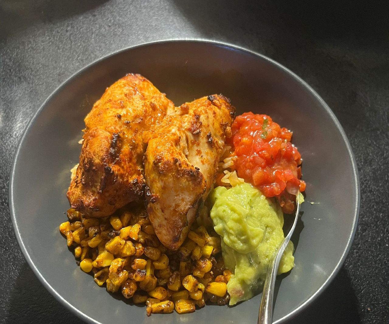 A bowl of cooked chicken breasts, salsa, guac, and charred corn.