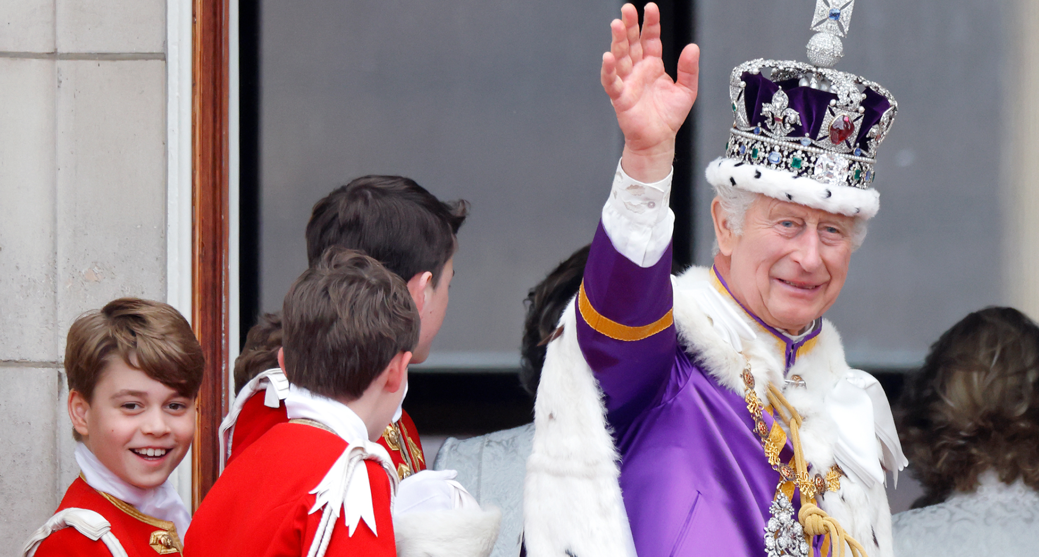 King Charles waving in his coronation crown and cape with Prince George smiling next to him