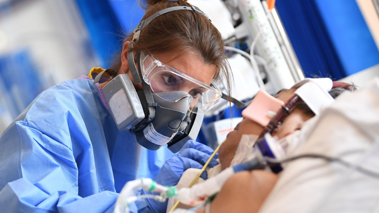 A doctor in PPE cares for a Covid patient.