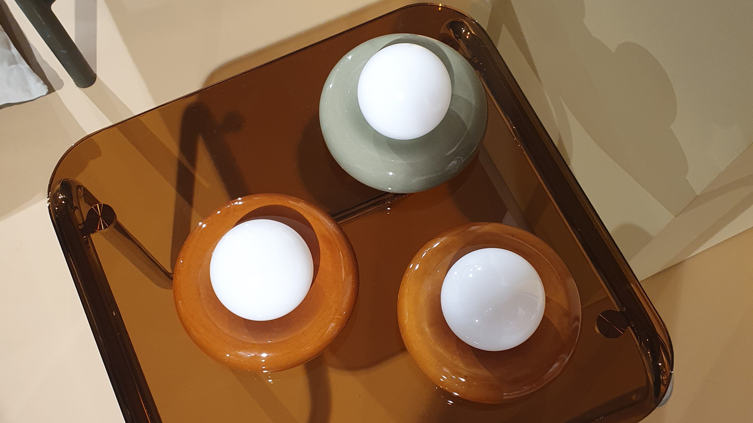 A brown glass side table displaying three donut-shaped lamps at the John Lewis spring/summer 2026 press show