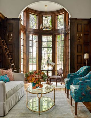 library with bay window curved alcove and turquoise chair and cream sofa