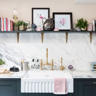 Butler kitchen sink with brass taps and books on shelf