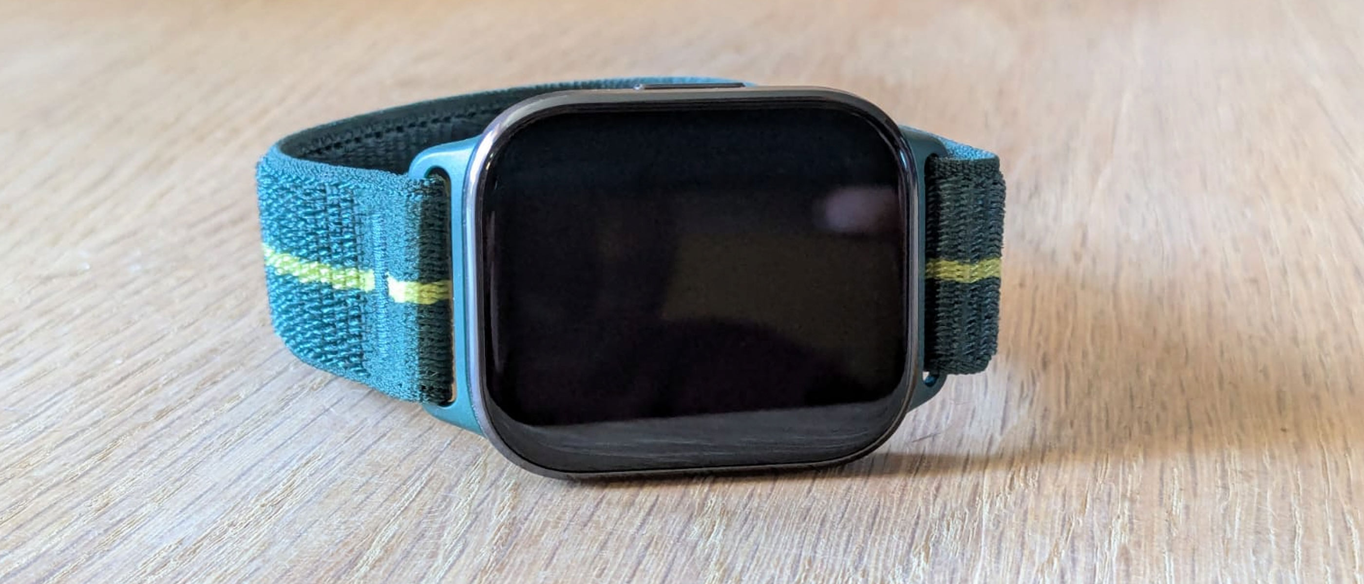 The Motorola Moto Watch Fit on a wooden table, screen of watch facing camera.