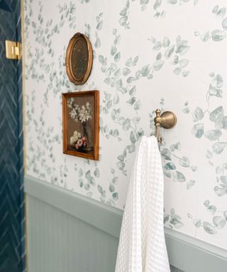 Brass hooks with waffle white towel and patterned wallpaper