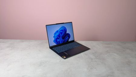 Three-quarter view of Lenovo Yoga Slim 7x Gen 11+ open on a desk with pink wall in background
