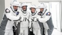 four people in white flight suits pose for a picture