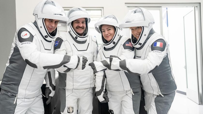 four people in white flight suits pose for a picture