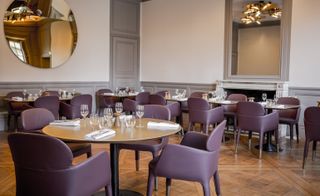 Purple leatherchairs, round/square tables, large round and rectangular mirror hang on surrounding walls