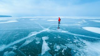 A woman in a red coat crossing a frozen lake