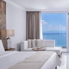 Photo of pristine beige hotel room overlooking the sea