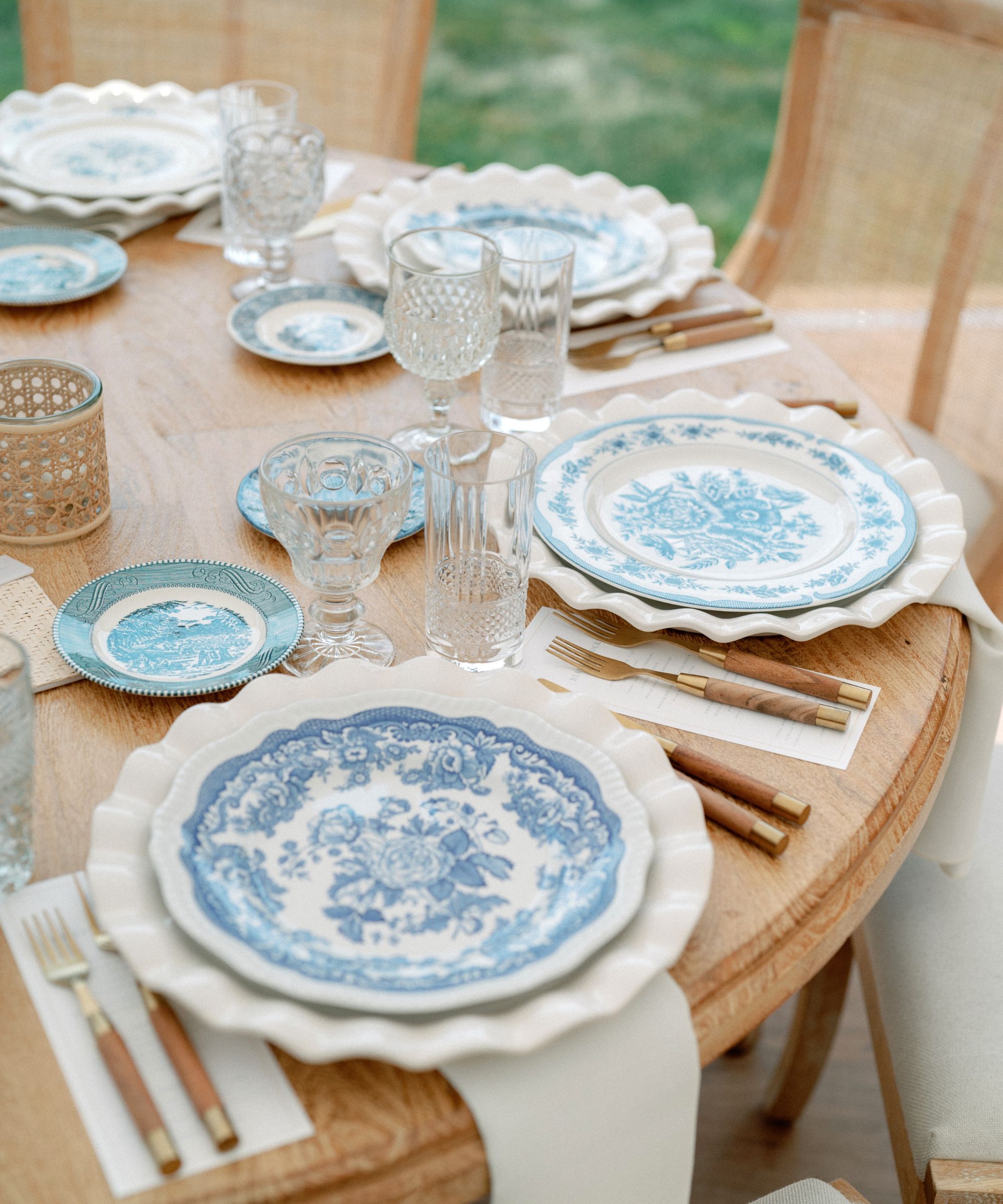 Wooden table outdoors set up with blue and white plates and wooden handled cutlery
