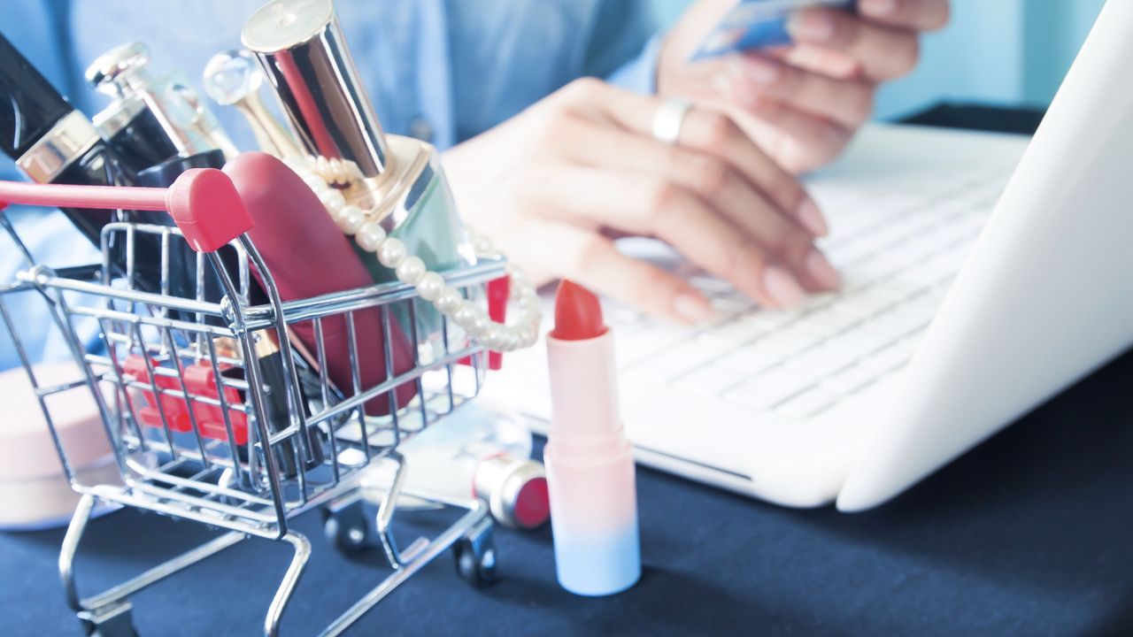 woman on her computer next to beauty products