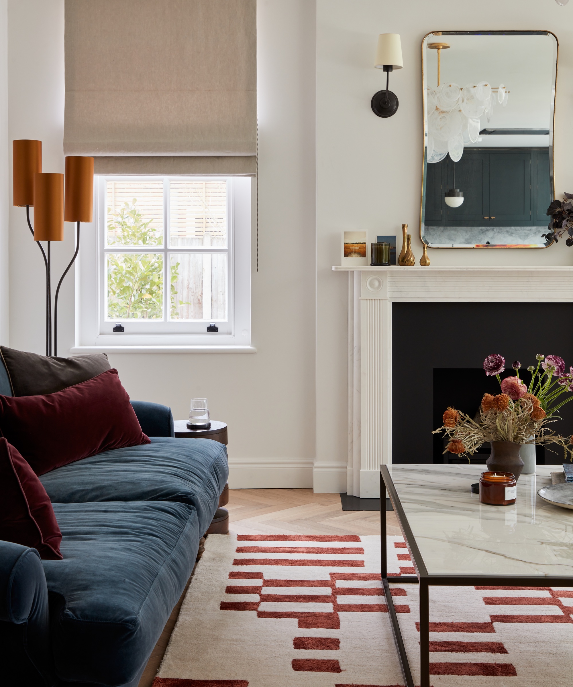 White living room with navy sofa and burgundy rug and cushions