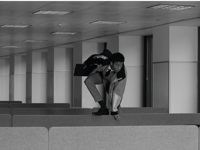 man in suit climbing over desks