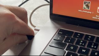 Shot of a hand plugging the webcam’s USB-C cable into a MacBook Air