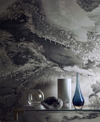 A nature inspired grey wallpaper by Anthology called Obsidian Panel with hallway console table with various glass vases on display