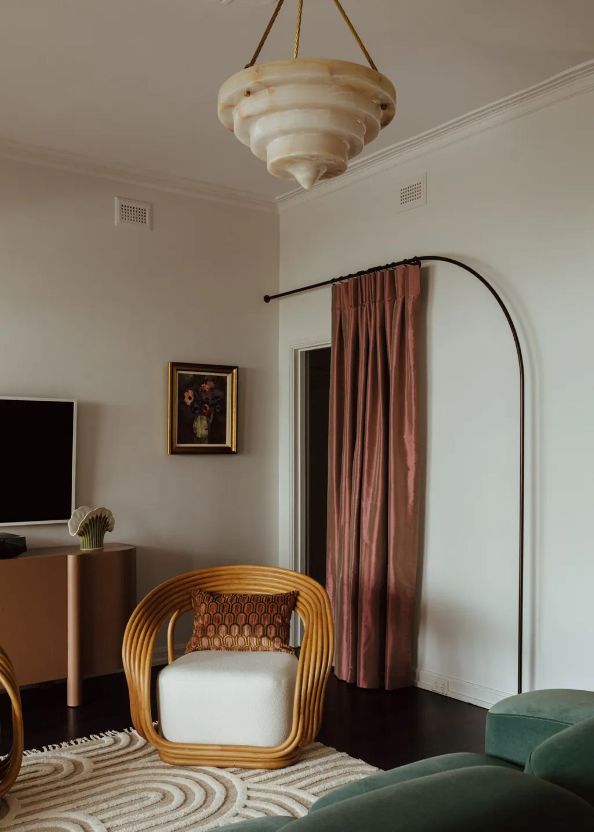 An art deco style living room with a hanging curtain, a pendant light, a textured rug and a cozy sofa chair