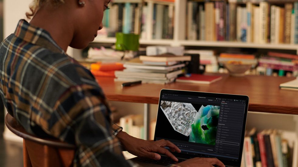 MacBook Pro M2 laptop open on a woman&#039;s lap in a library