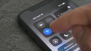 An image of an iPhone showing a finger tapping the Wi-Fi button on Control Center, representing an article about how to set up a Wi-Fi hotspot on iPhone