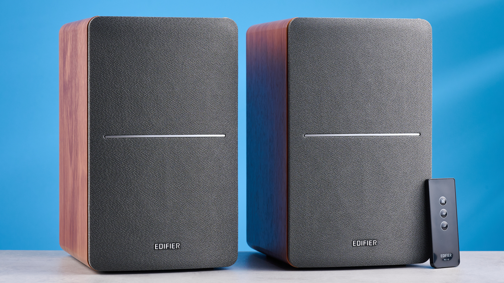 the edifier r1280t bookshelf speakers in wood brown photographed against the blue background, showing the volume adjustment dials, internal drivers and tweeters, RCA and aux inputs, and remote