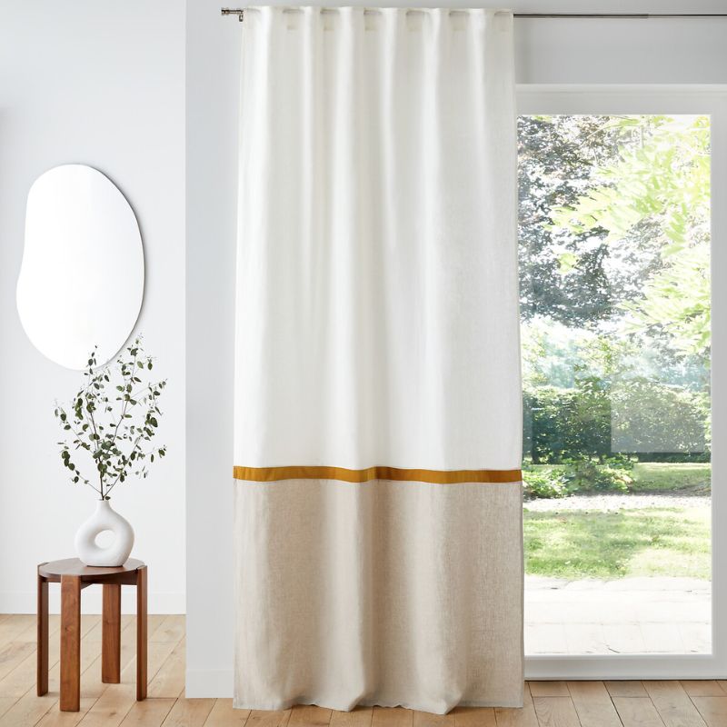 white curtains with beige lower section and ecru stripe, in neutral room with white wall and glass doors