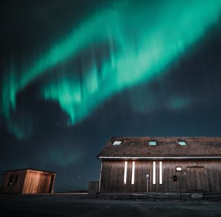 A wooden building underneath the northern lights