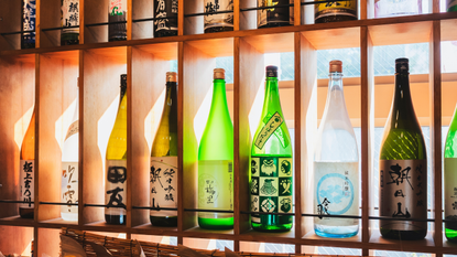 Bottles of sake lined up on a shelf.