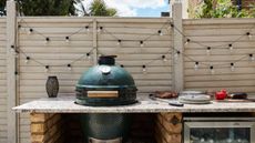 A green egg grill in an outdoor kitchen setup with festoon lighting