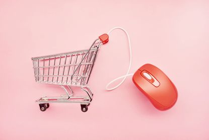 Small shopping cart and red computer mouse on pink background