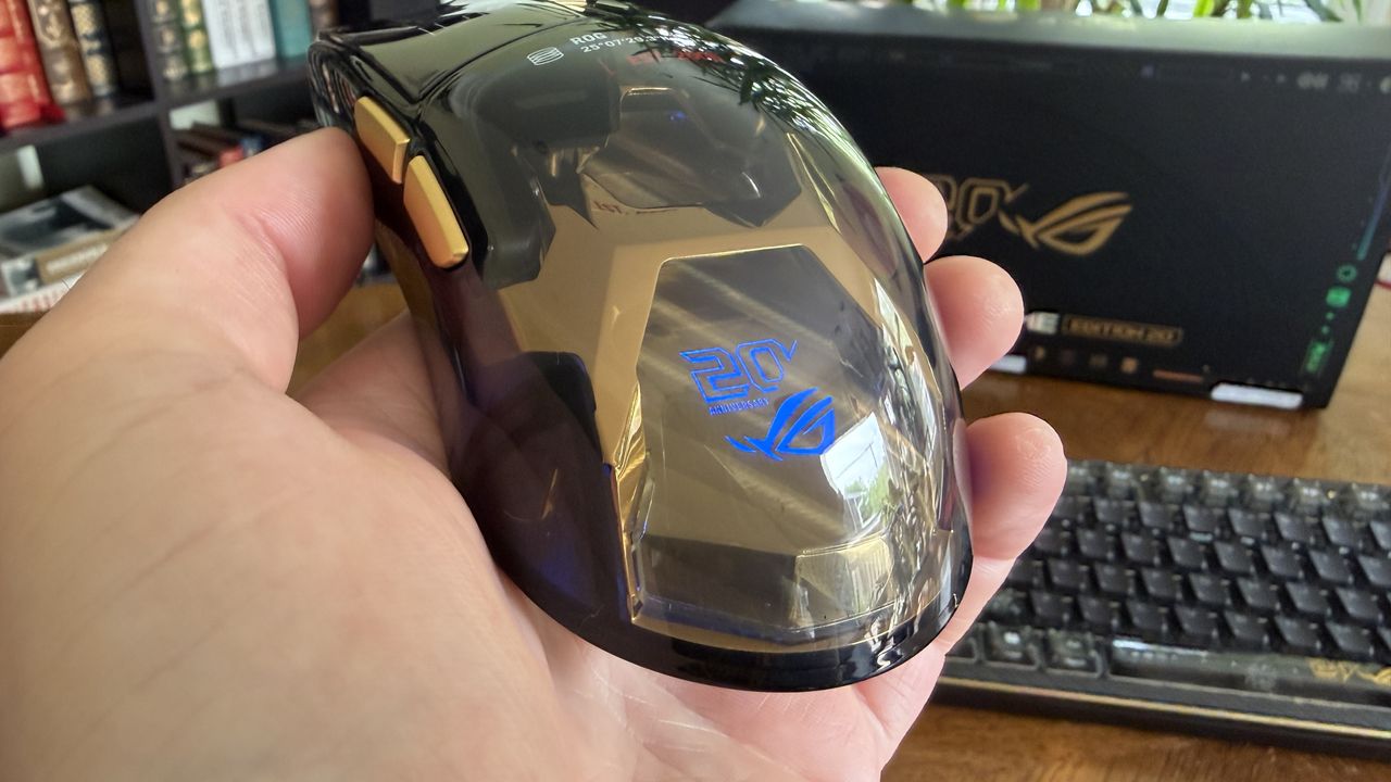 A 20th Anniversary edition ASUS ROG computer mouse with a reflective surface and golden accents.