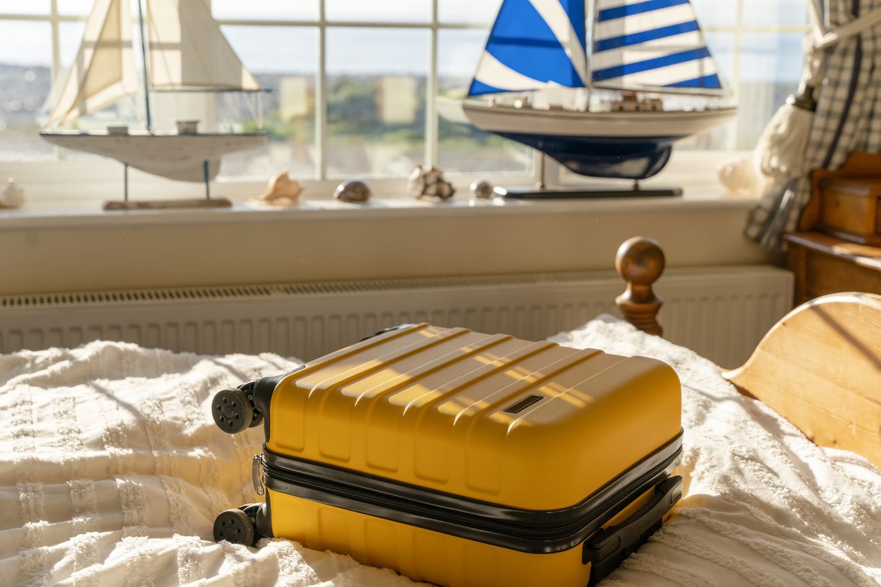 Holiday rental with yellow suitcase on bed