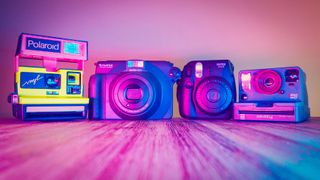 Instax vs Polaroid – the Polaroid 600 Vnyl and Polaroid OneStep 2 Stranger Things cameras, positioned next to the Instax Mini 8 and Instax Wide 100 cameras, lit with neon lighting