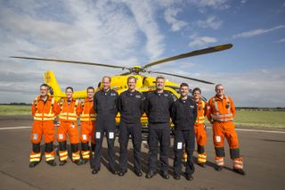 Prince William, Duke of Cambridge (4L) poses for a final photo with both day and night shift crews