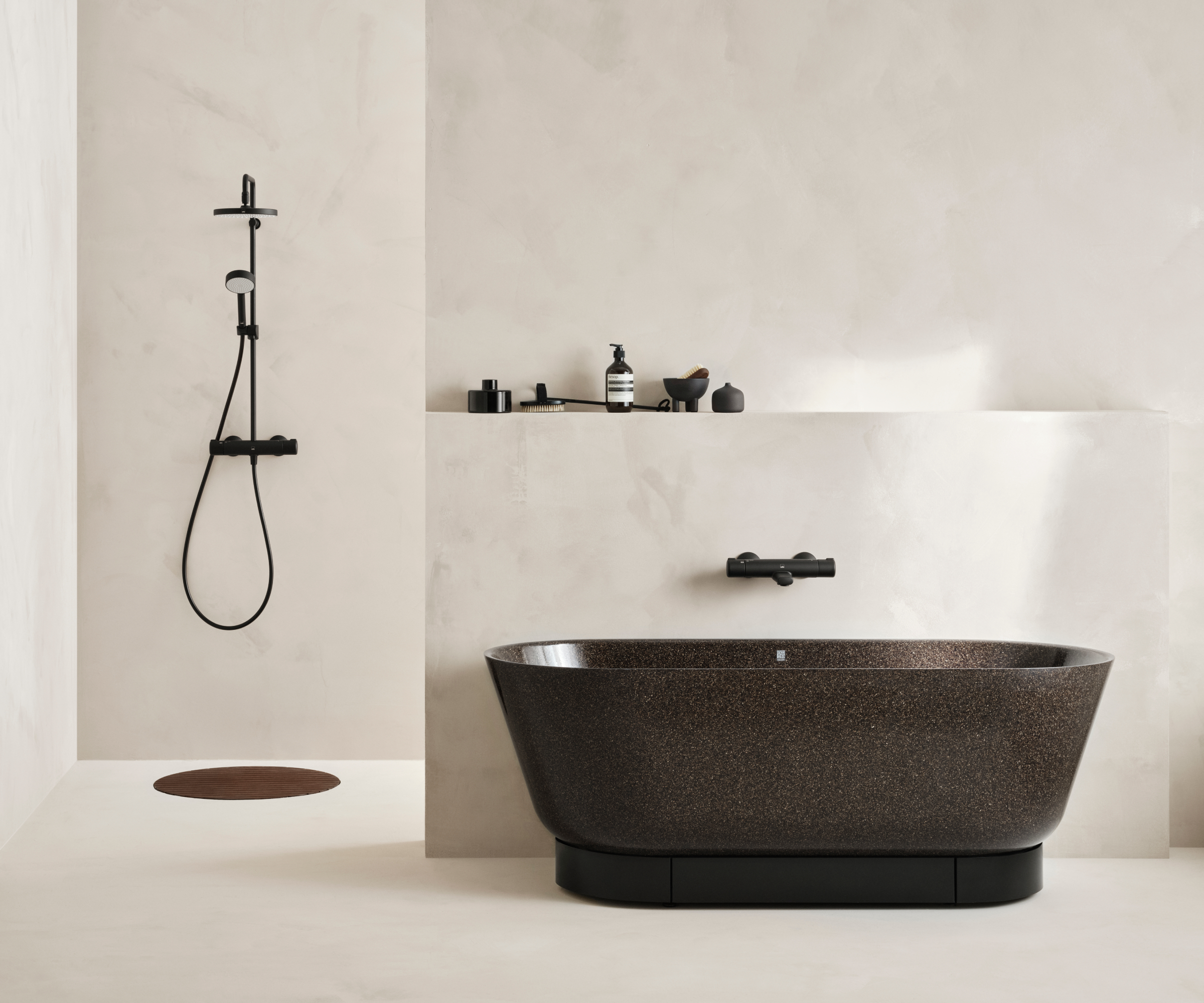 minimalist bathroom with dark freestanding bath and walls and floors finished in cream panels, large bronze shower drain and shower