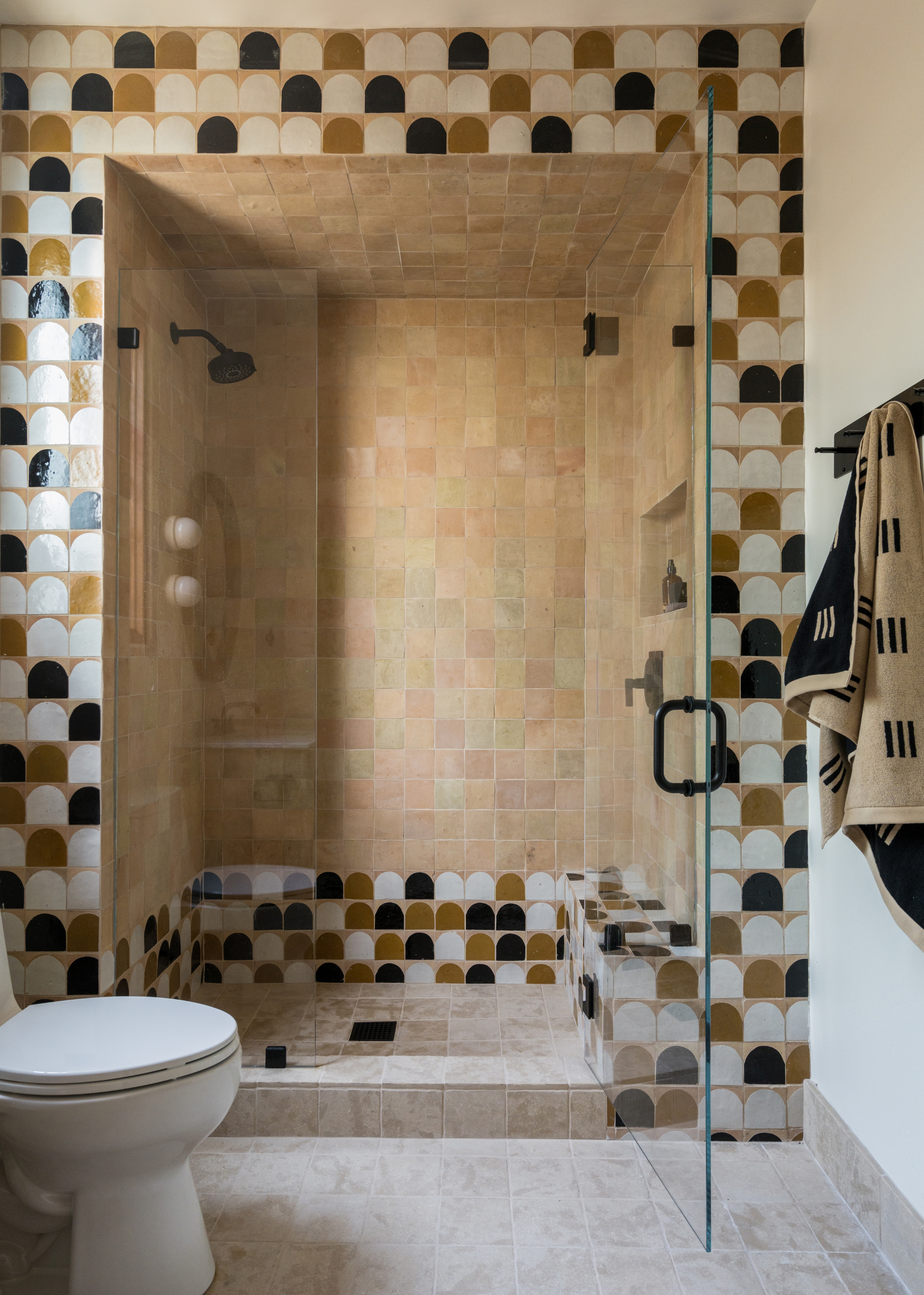 a huge walk-in shower with a zellige half moon trim and nude zellige walls