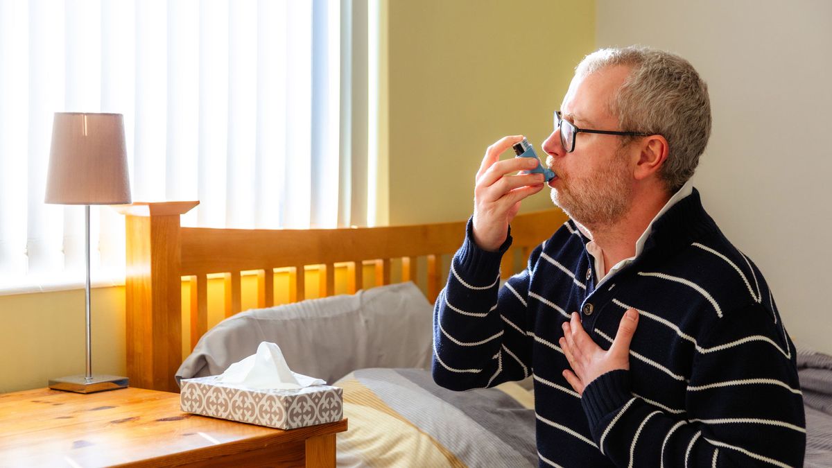 Can air purifiers help with asthma? Image showing an elderly man using an asthma inhaler in his bedroom