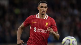 Trent Alexander-Arnold runs after a bouncing ball in his all-red Liverpool home kit.