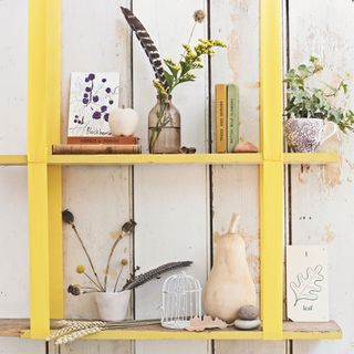 wooden wall with yellow shelves and pots and books